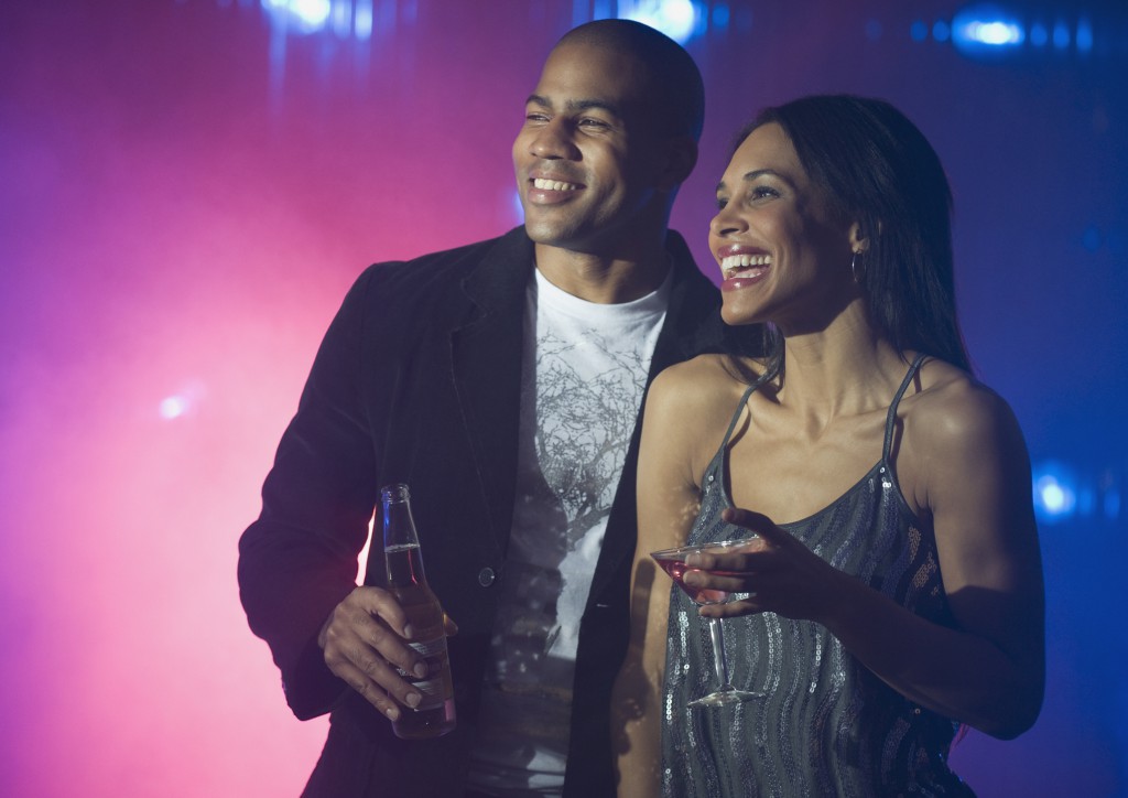 Boyfriend and girlfriend holding drinks at nightclub