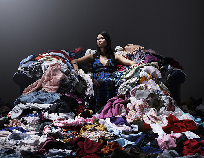 Woman sitting on sofa surrounded by clothes.
