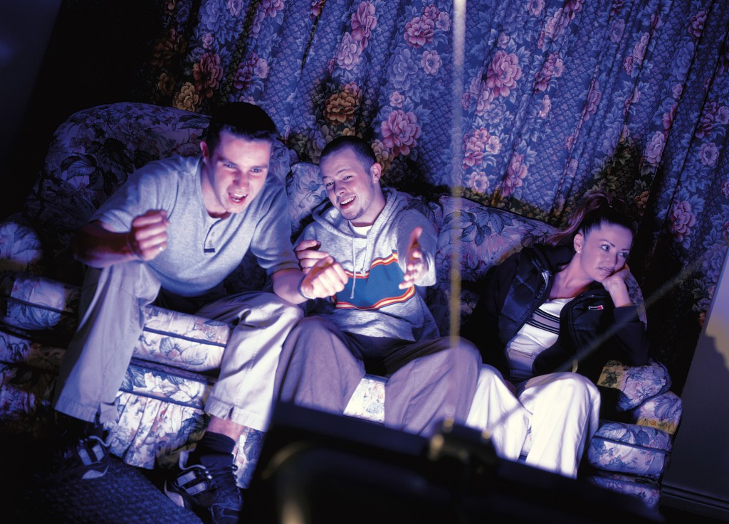 three young people sitting on a couch watching television
