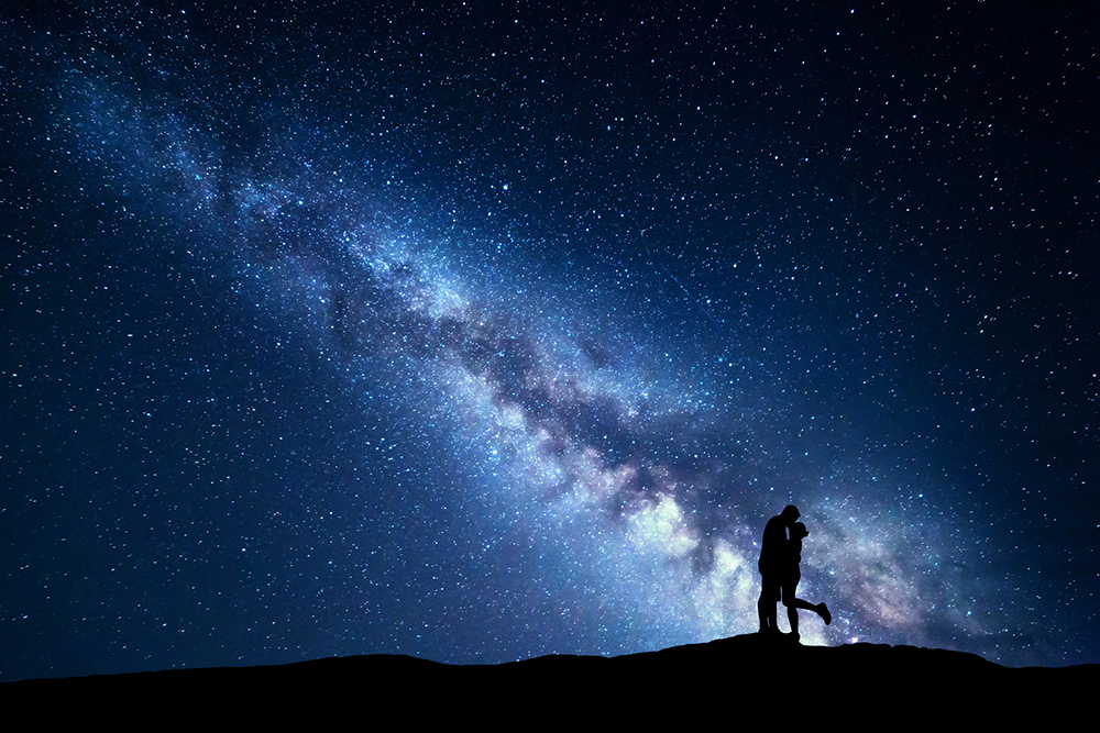 Milky Way. Silhouettes of hugging and kissing man and woman