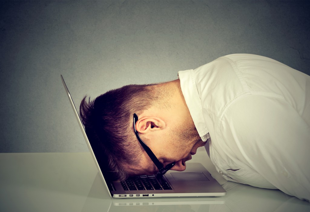Desperate employee stressed man resting head on laptop