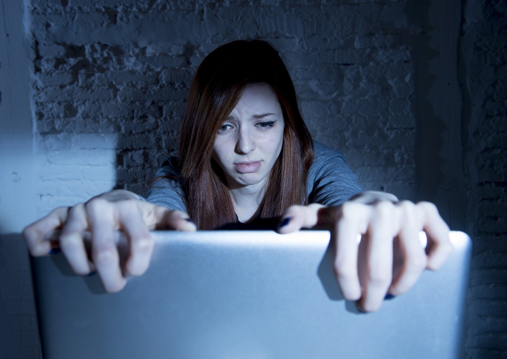scared female teenager with computer laptop suffering cyberbullying harassment
