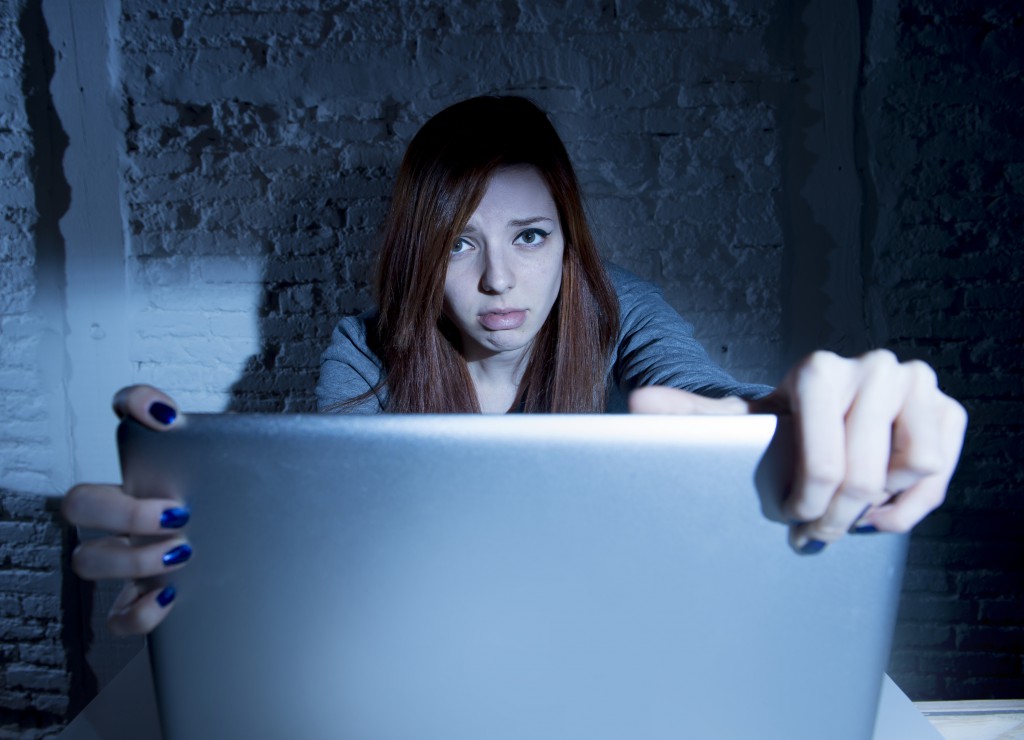 scared female teenager with computer laptop suffering cyberbullying harassment