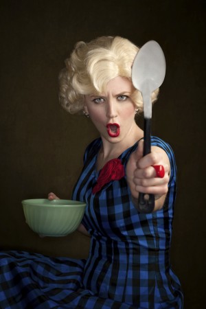 Pretty retro blonde woman in vintage 50s dress with bowl and spoon