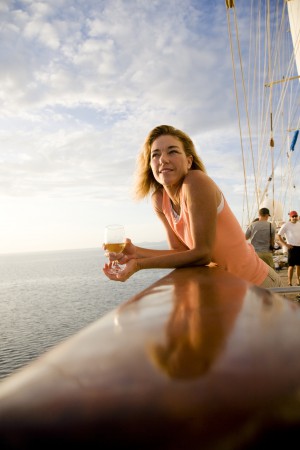Woman holding a glass of wine on a sailboat, Tahaa, Tahiti, French Polynesia