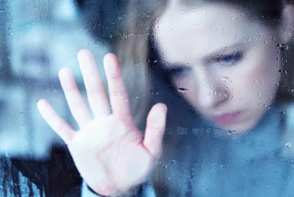 melancholy and sad girl   at window in the rain