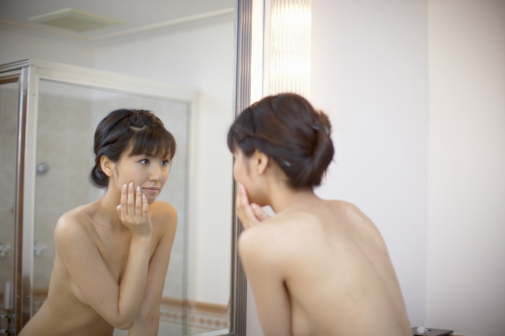 Young woman looking in bathroom mirror, close-up